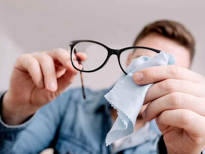 Somebody cleaning their prescription glasses with cleaning products from Dynamic Vision Optometrists