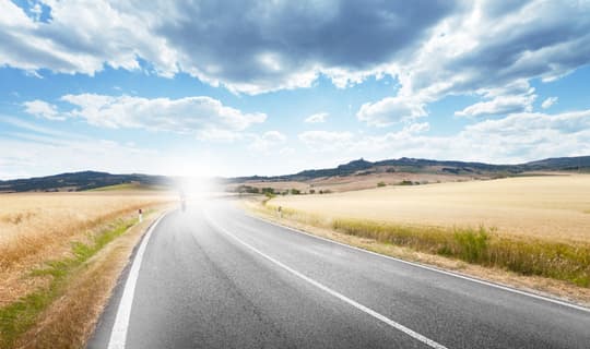 Country road with intense glare and washed-out colours through normal lenses, illustrating the clarity benefit of SEIKO Polarised Sun Lenses at Dynamic Vision Optometrists in South Africa